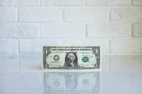 One US dollar bill by the wall (Photo by Kenny Eliason on Unsplash)